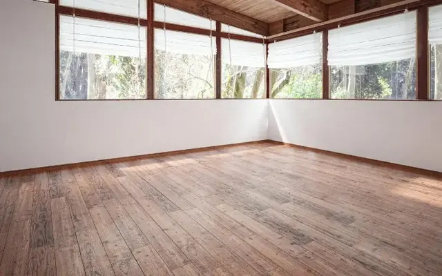 Salón vacío con suelo de madera tras retirar los muebles